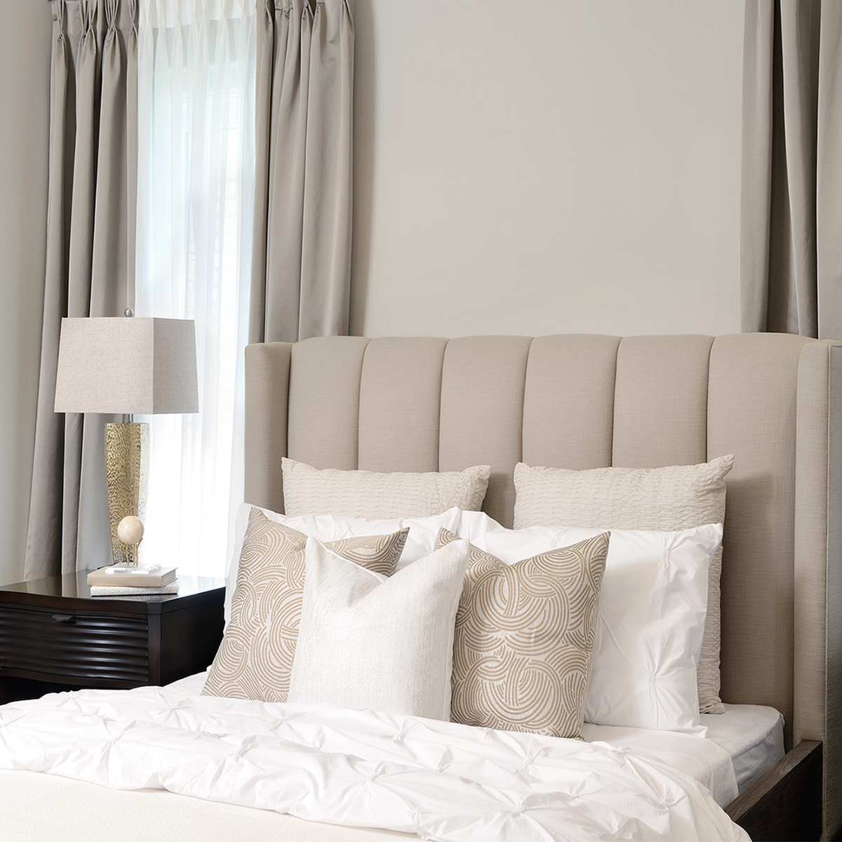 tall fabric headboard with matching white and beige throw pillows on the bed